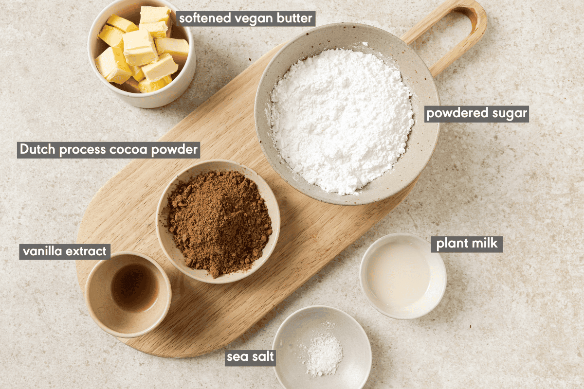Ingredients for vegan chocolate frosting in various bowls with ingredients labeled.