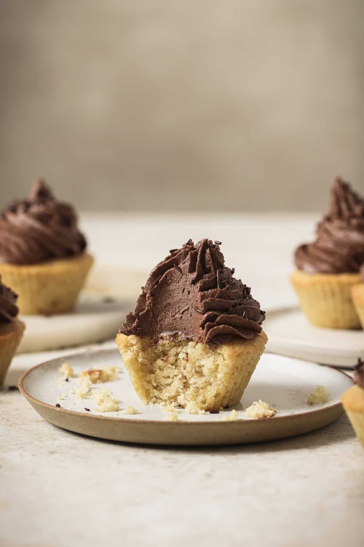 Cupcake with a bite taken out of it on a plate.