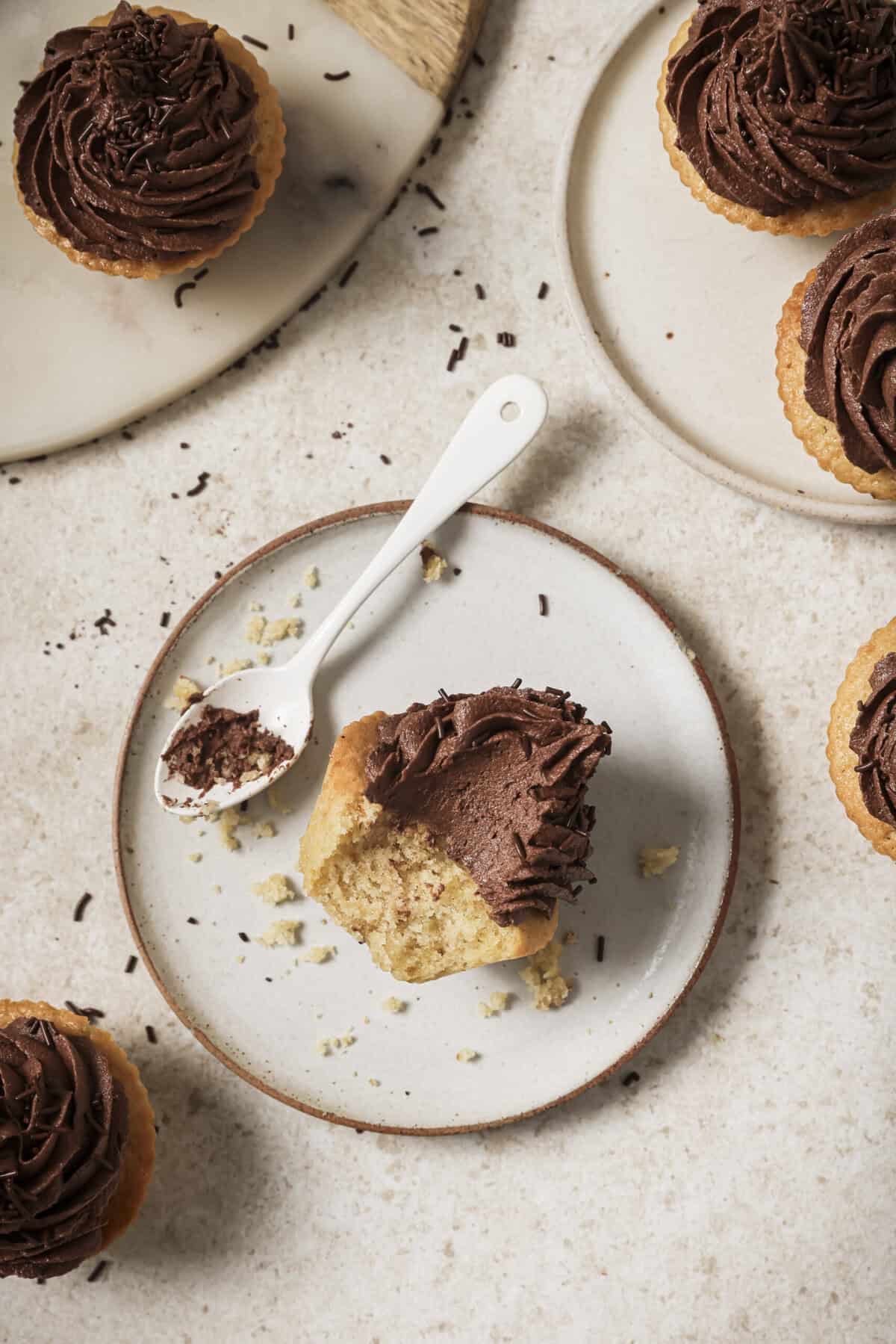 Overhead view a half eaten cupcake and spoon on a plate.