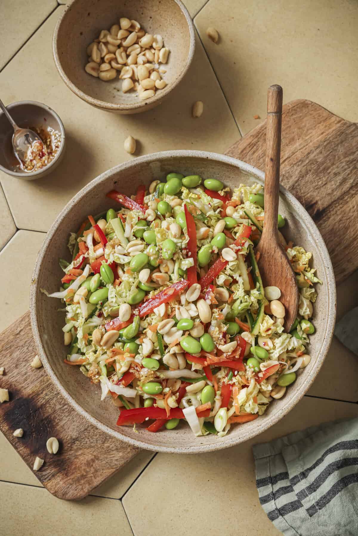 overhead view of salad with a wooden spoon on a wooden cutting board.