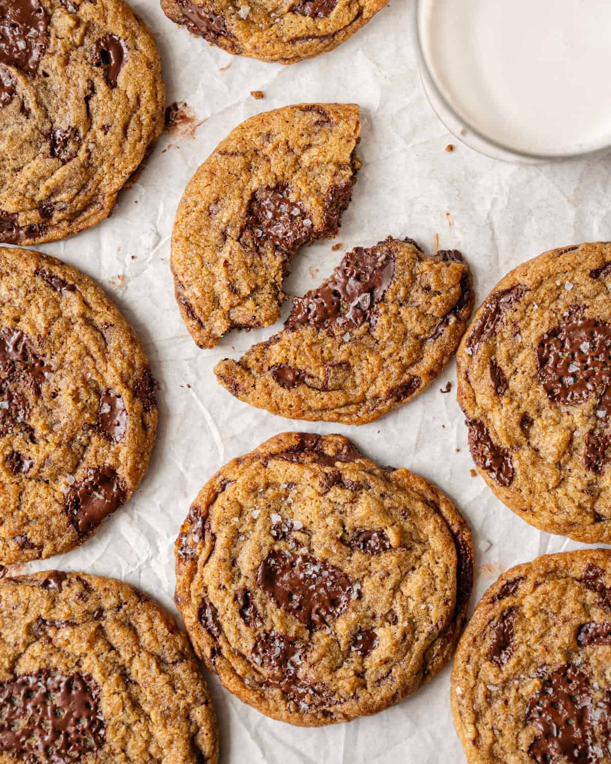 several chocolate chip cookies on parchment paper with one in half.
