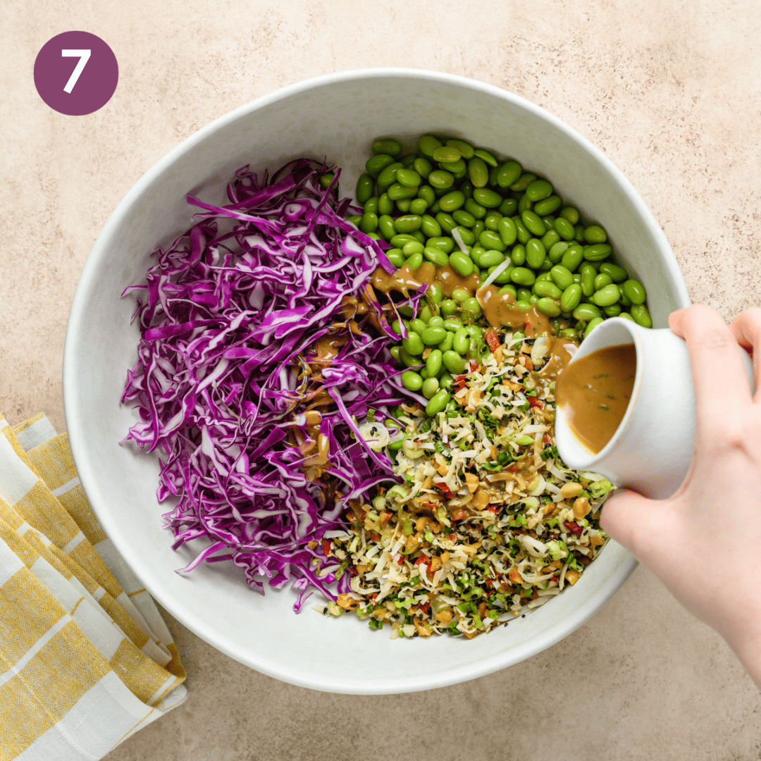 Person pouring dressing over salad components before mixing.