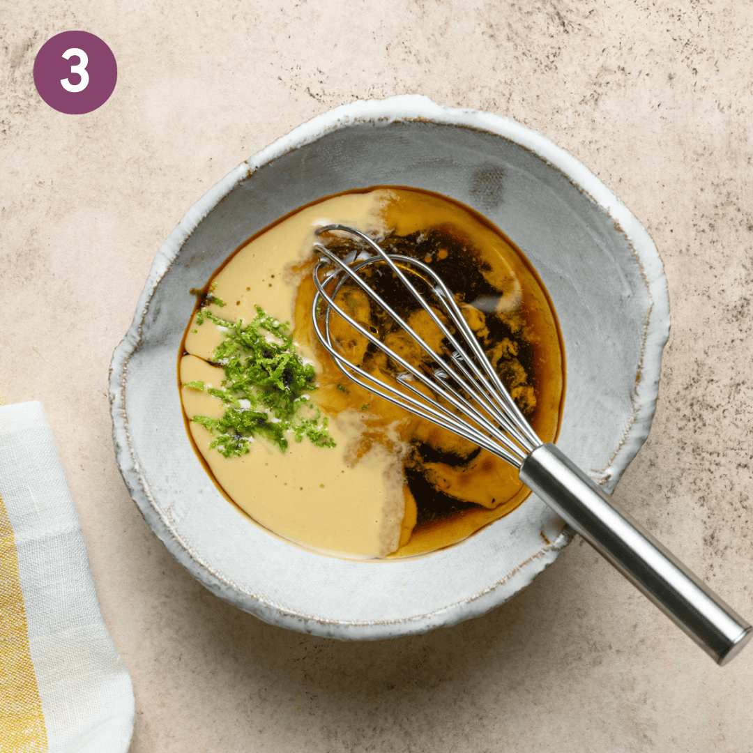 Dressing ingredients in a small bowl with a whisk.