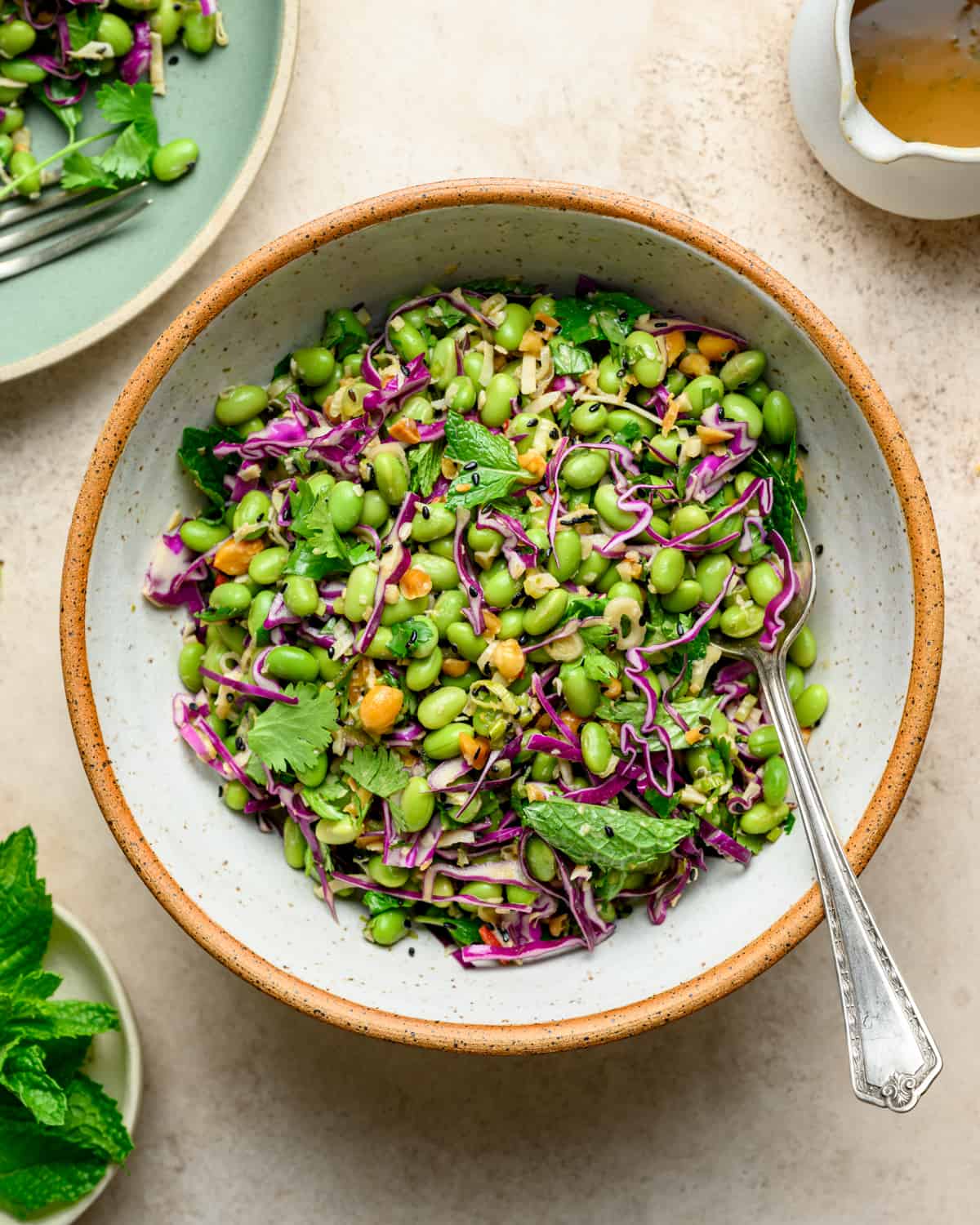 Bowl of edamame salad with a spoon on a table.