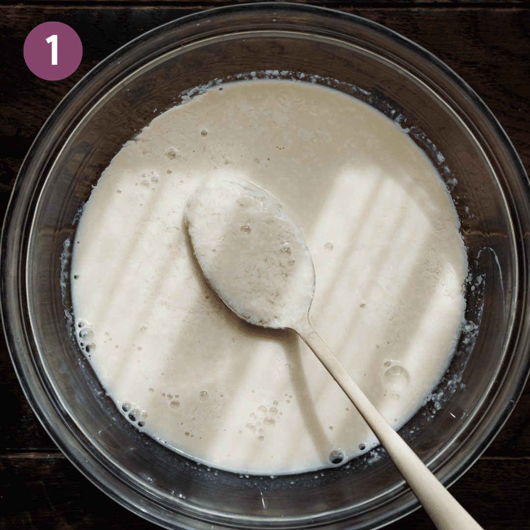 bowl of curdled vegan buttermilk with a spoon on a wooden table.