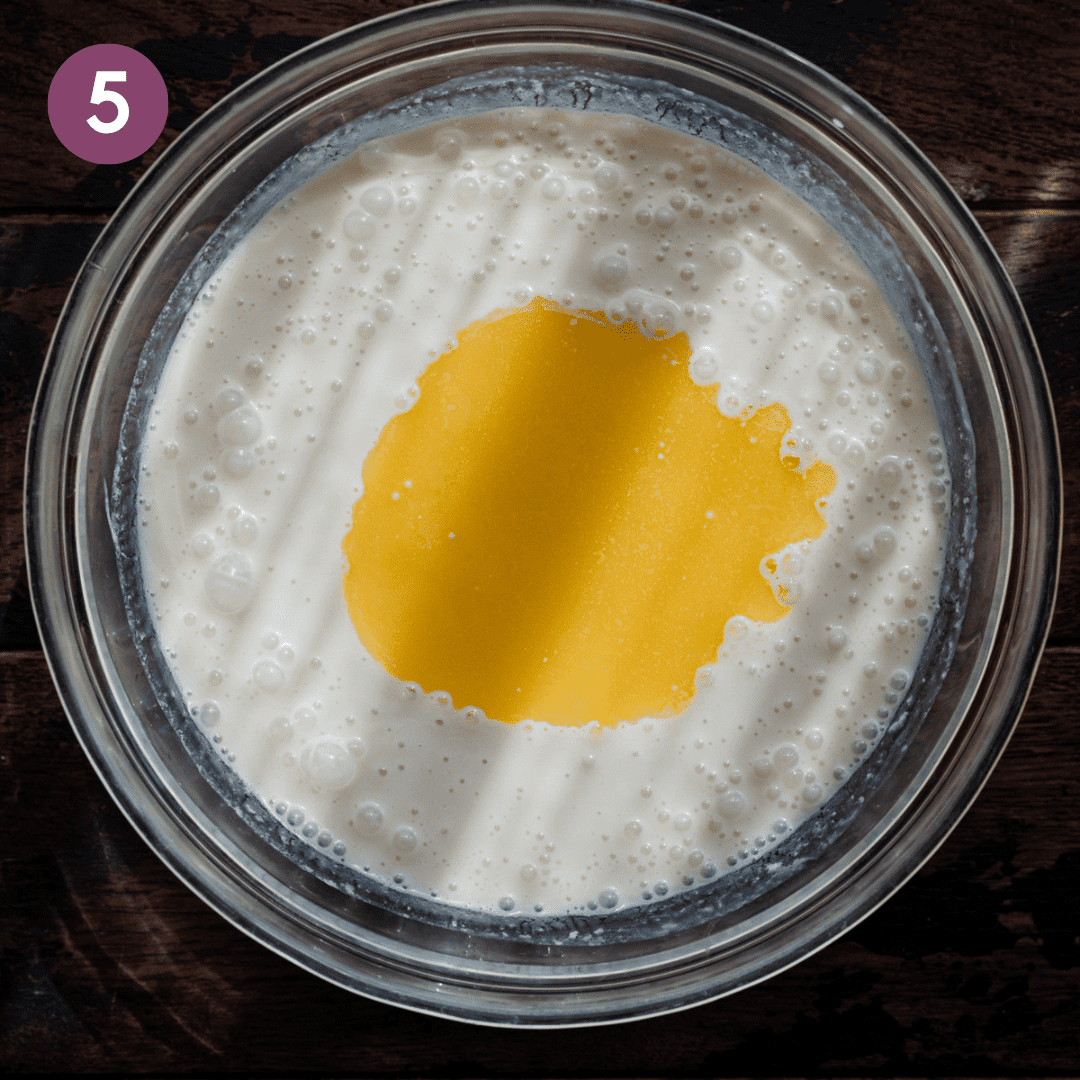 pool of melted butter in the middle of liquid ingredients for pancakes in a glass bowl.