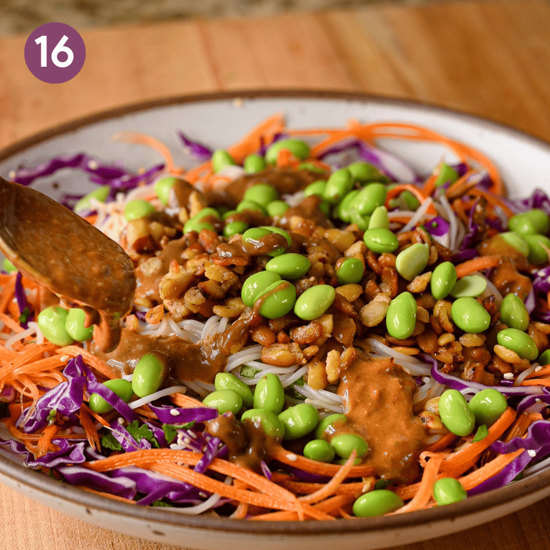 person spooning peanut sauce onto bowl.