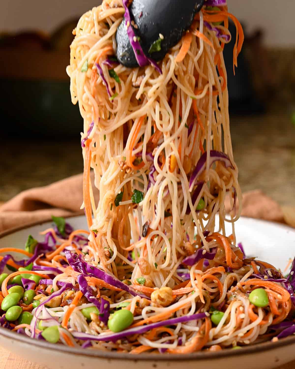 tongs lifting noodles from plate.