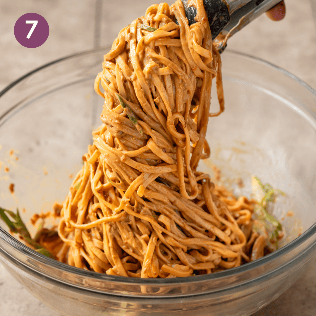 person picking up noodles with tongs out of the glass bowl.