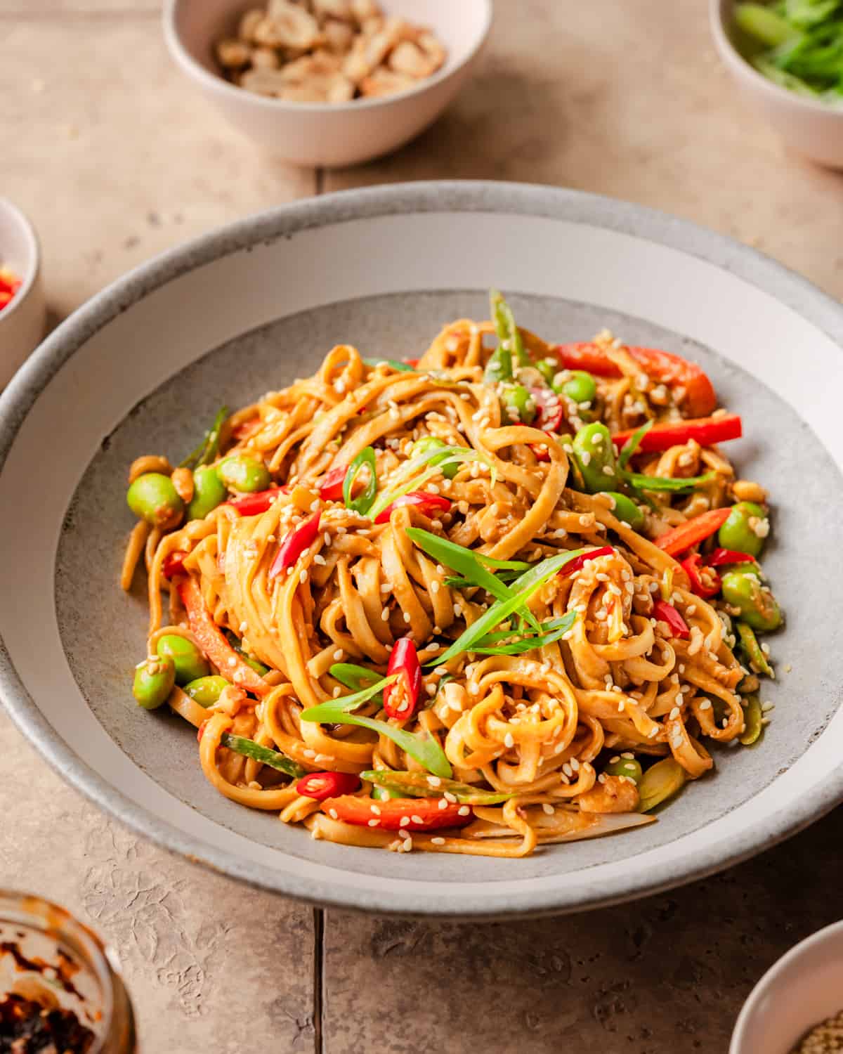 side view of sesame noodles in a bowl on a table.