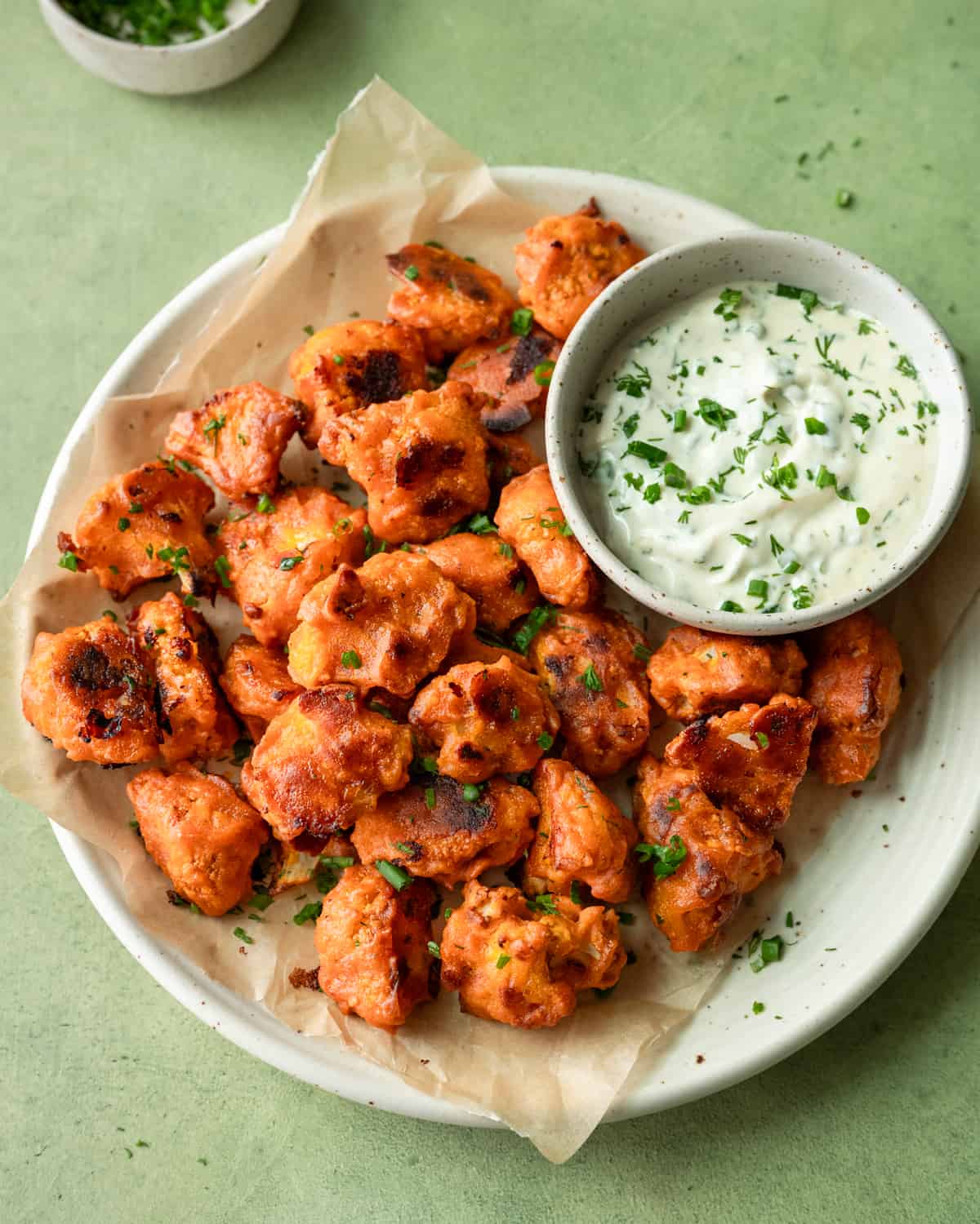 overhead view of plate of buffalo cauliflower with bowl of ranch on a table.