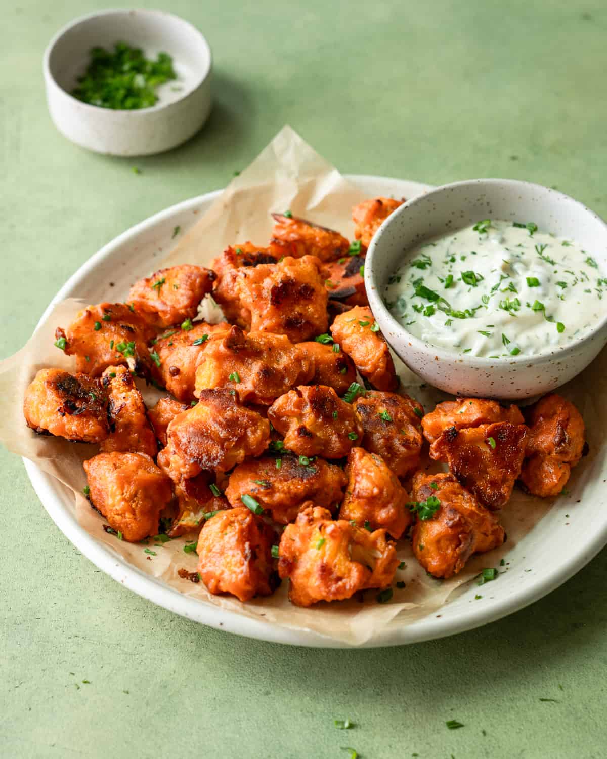 side view of plate of buffalo cauliflower with bowl of ranch on a table.