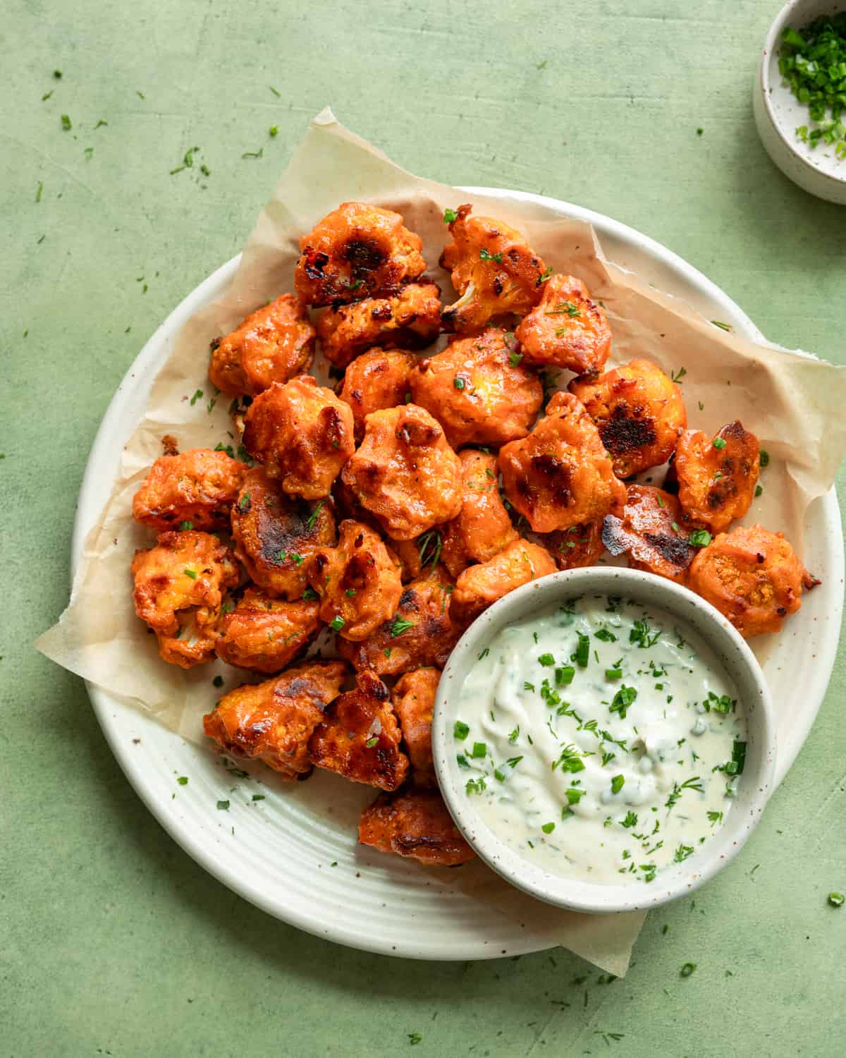 far up view of plate of buffalo cauliflower with bowl of ranch on a table.