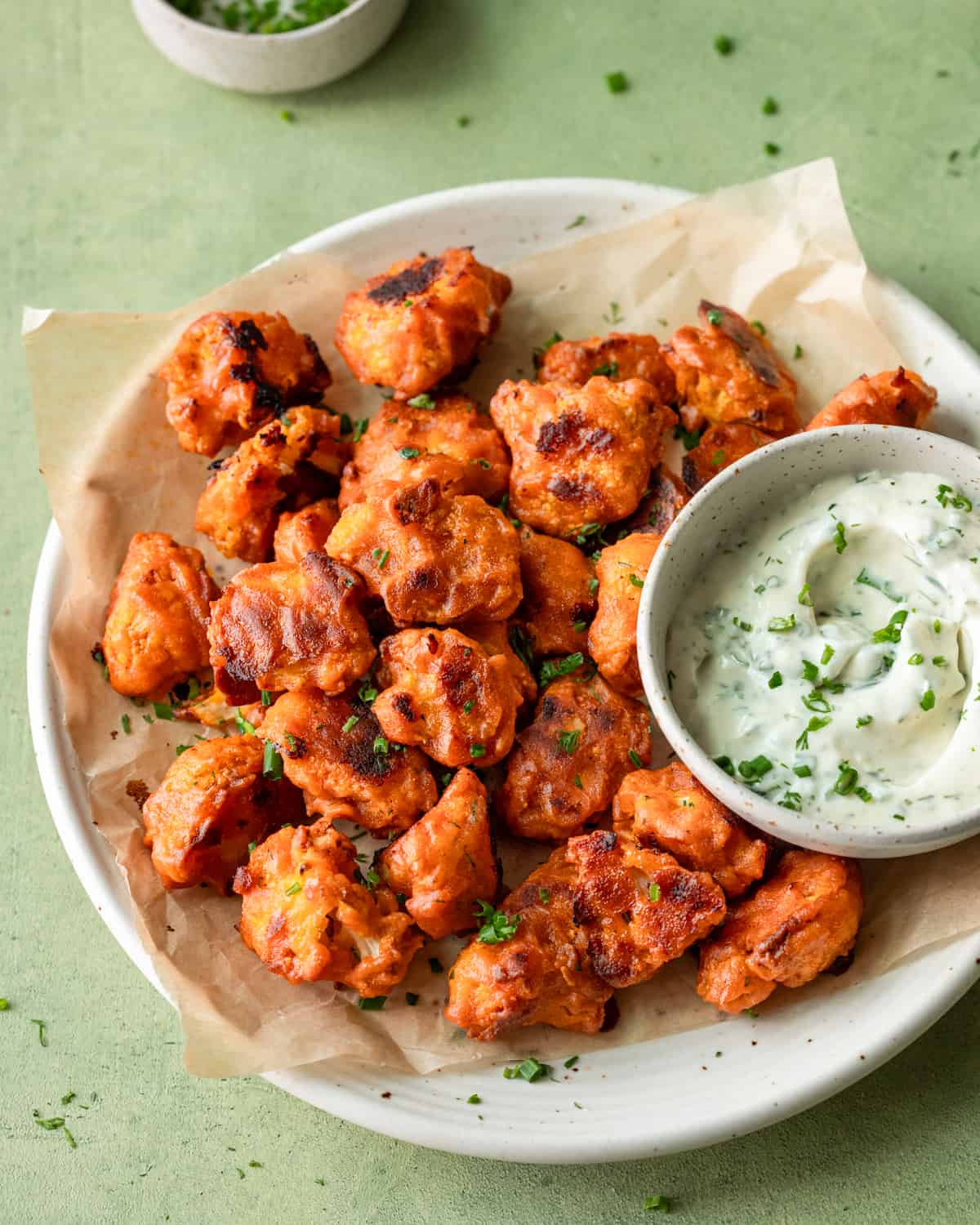 overhead view of plate of buffalo cauliflower with bowl of ranch on a table.