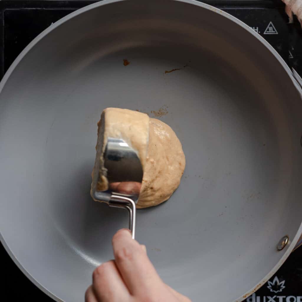 woman's hands pouring pancake batter into skillet