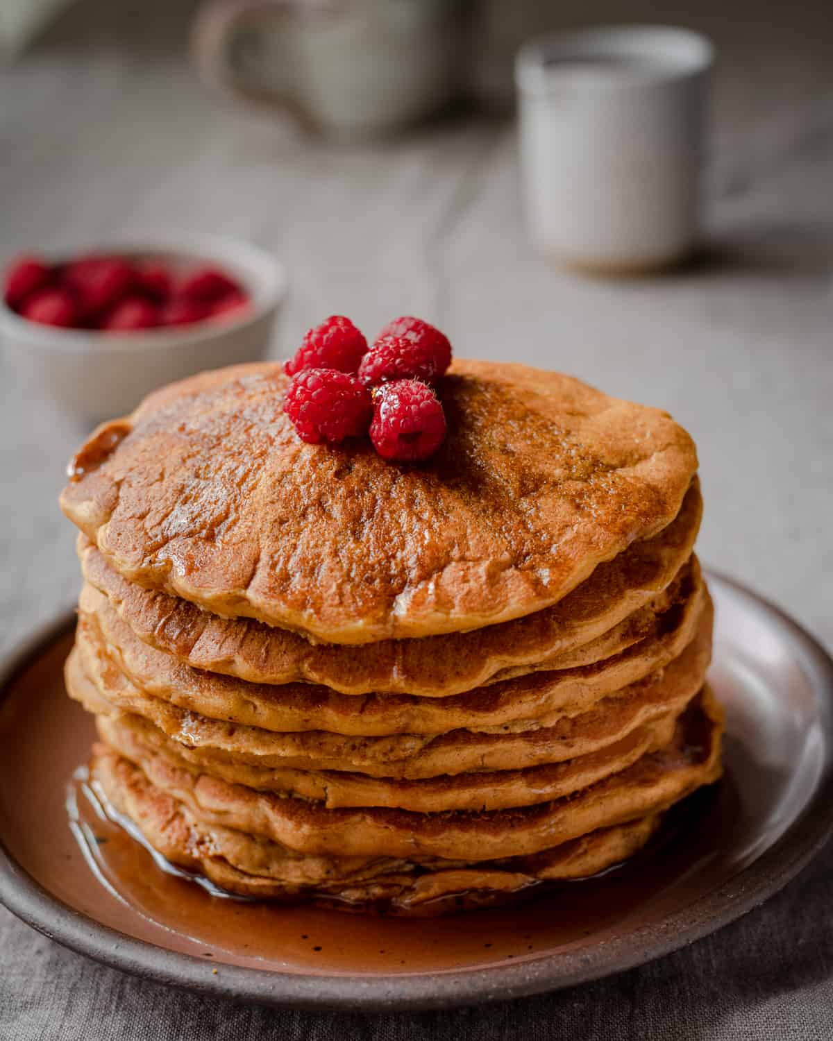 a stack of vegan pumpkin pancakes with raspberries on top