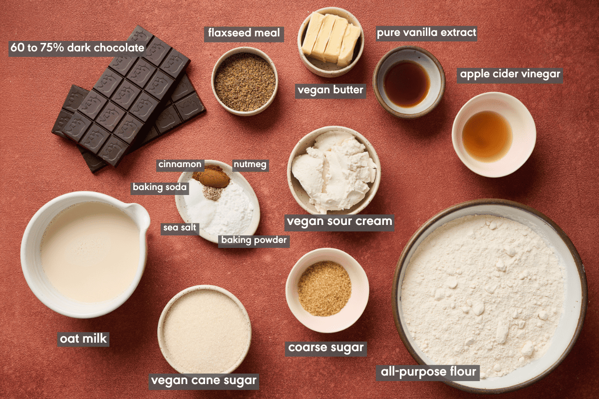 Vegan chocolate chip muffin ingredients in various bowls on a red table.