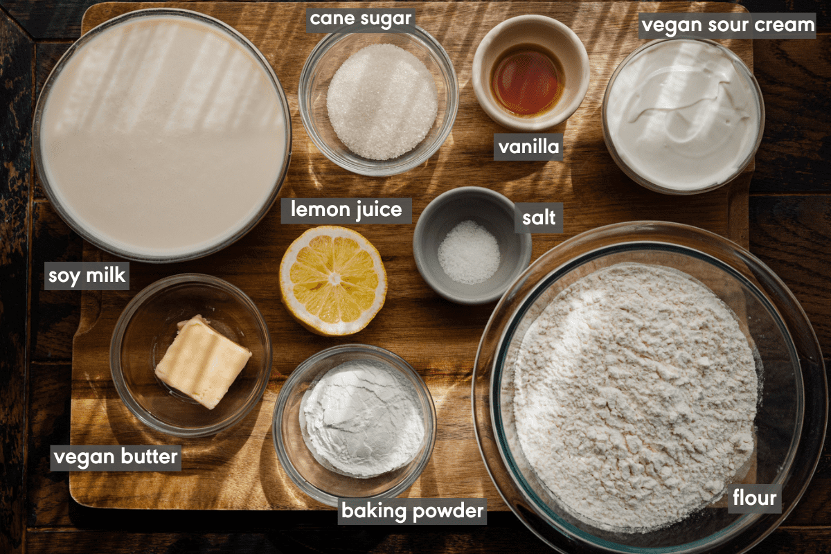 ingredients for vegan pancakes in bowls on a wooden cutting board with ingredients labeled.